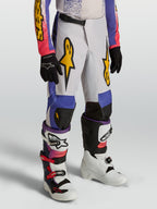 Alpinestars Youth Fluid Drag, calças de motocross para jovens em azul e roxo com gráficos dourados e design ergonómico.