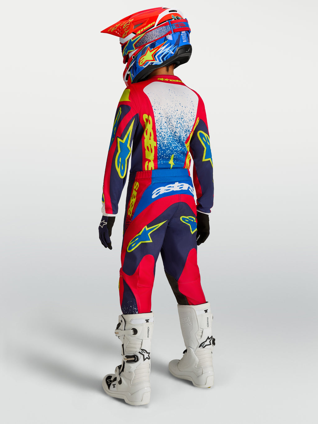 Alpinestars calças Fluid Drag juventude, calças de motocross azul-marinho e vermelho, vista traseira com botas brancas.