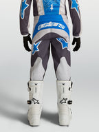 Alpinestars Calças Fluid Drag Juventude, calças de motocross azuis e cinzentas com ajuste pré-curvado, vista traseira.