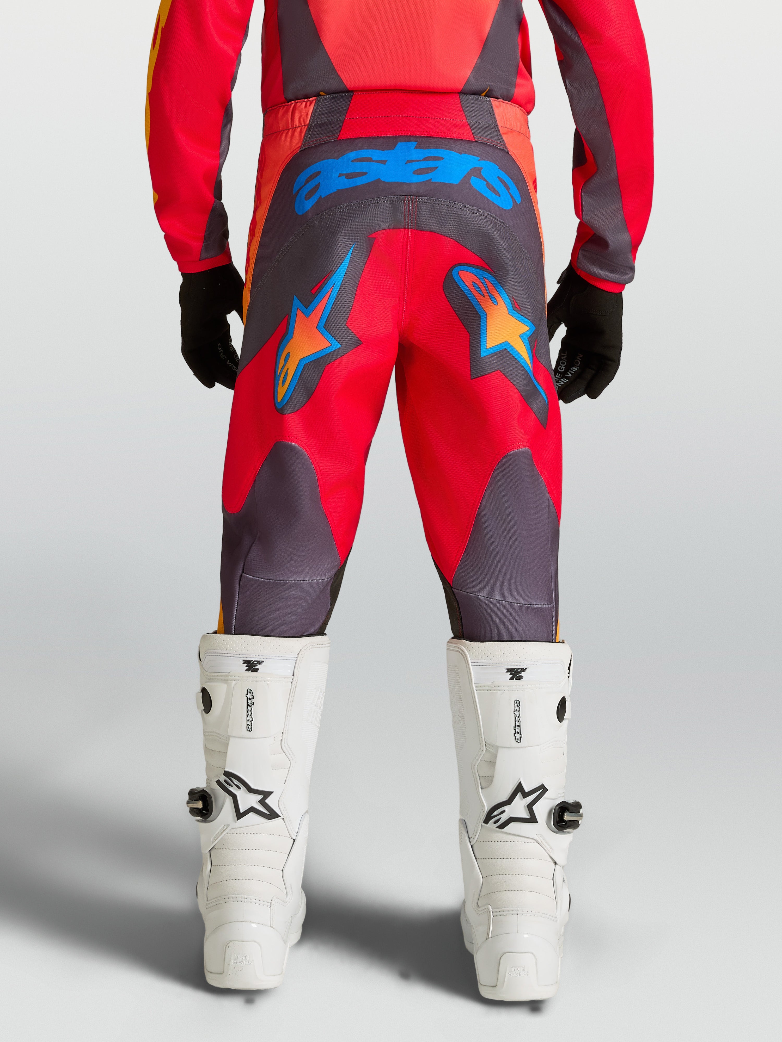 Alpinestars Calças Fluid Hunt Juventude, calças de motocross vermelhas e cinzentas com estrelas azuis, vista traseira.