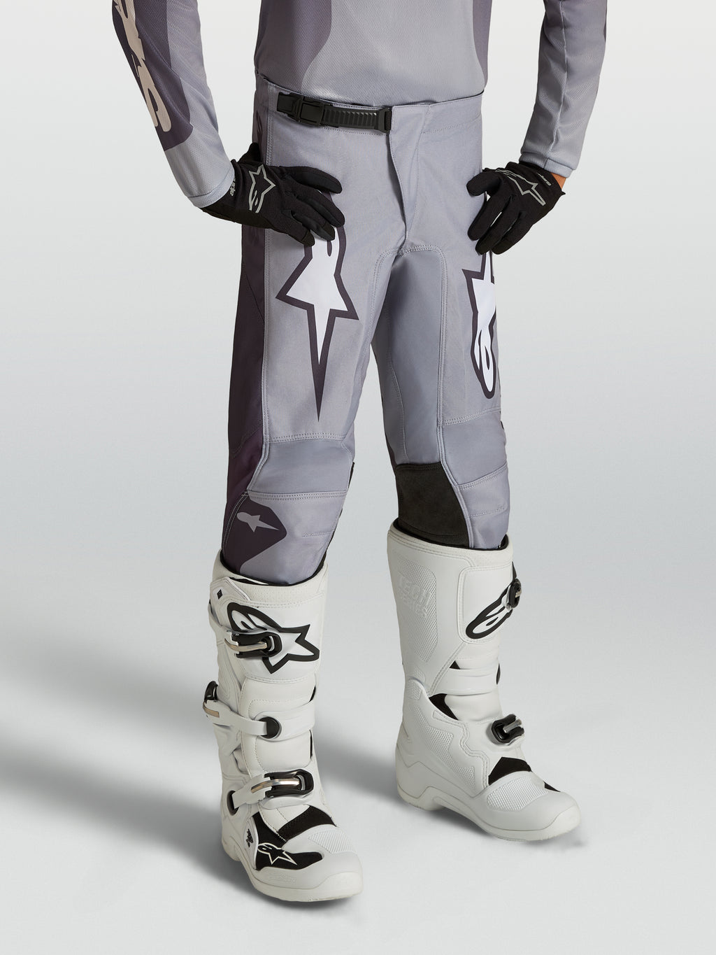 Alpinestars Fluid Amber Juventude, calças de motocross em cinzento areia com gráficos brancos e painéis reforçados.