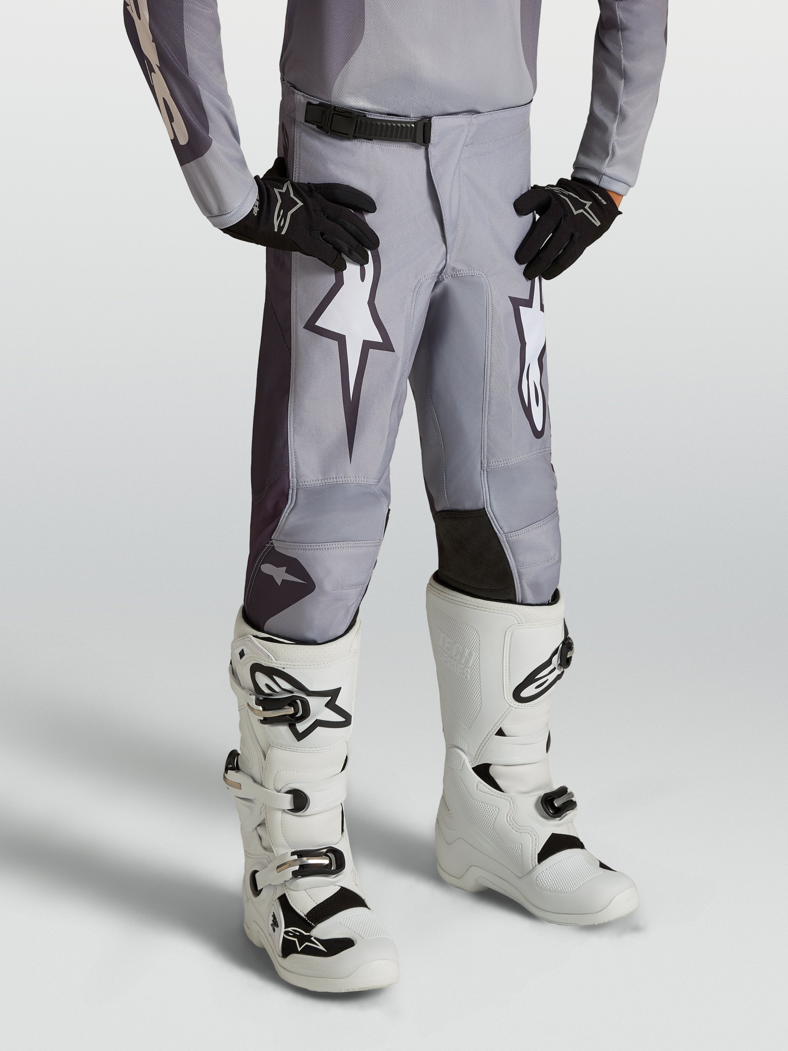 Alpinestars Fluid Amber Juventude, calças de motocross em cinzento areia com gráficos brancos e painéis reforçados.