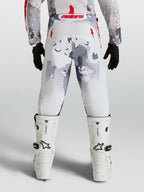 Alpinestars calças Fluid Lone Juventude, calças de motocross em cinzento camuflado e branco com detalhes em vermelho, vista traseira no piloto.