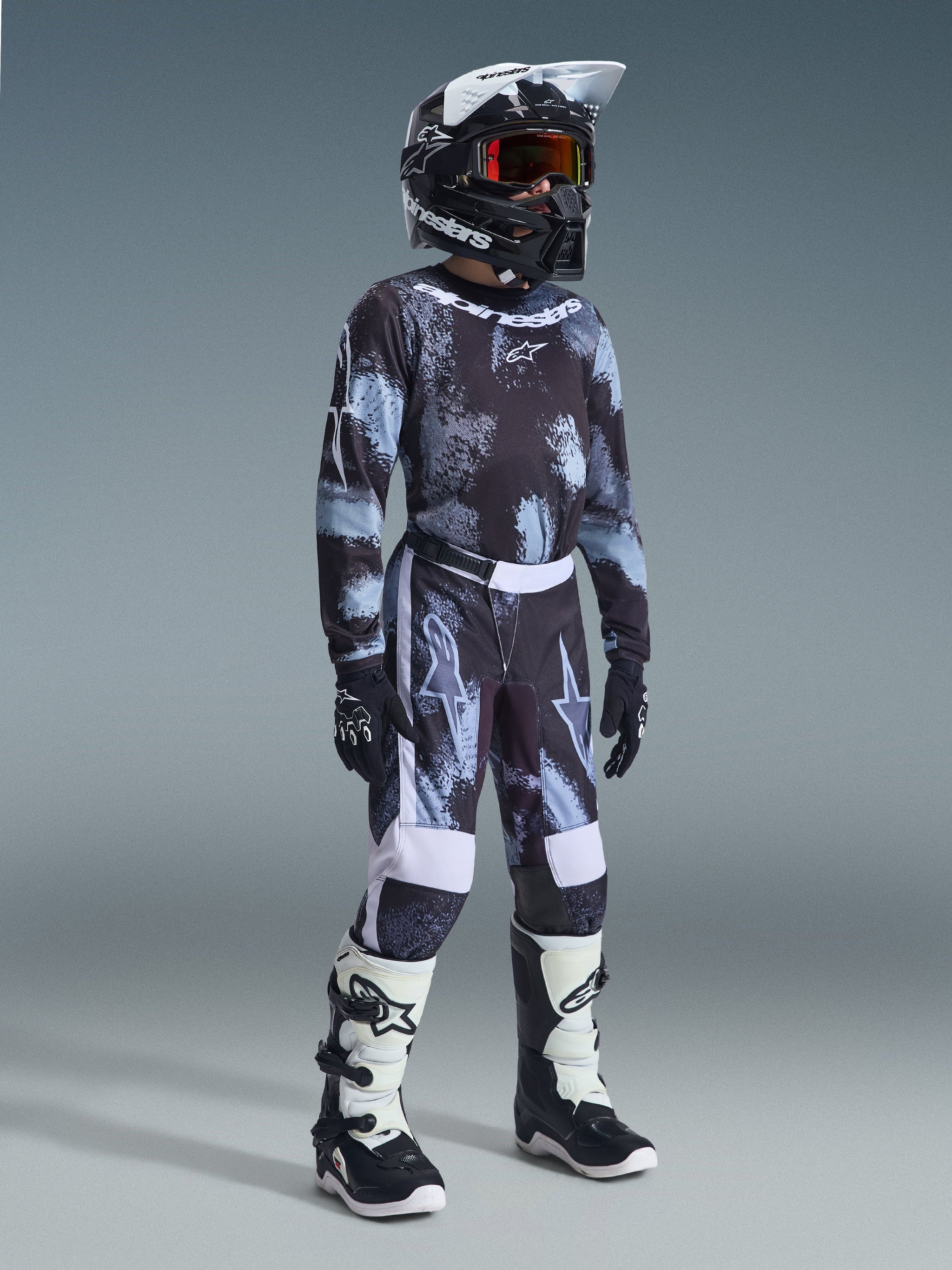 Alpinestars 2026 Youth Fluid Lahnd Pants, calças de motocross para jovens, Iron Camo, conjunto de corrida completo com camisola a condizer, capacete preto e botas brancas e pretas, equipamento de off-road de alta performance para jovens pilotos