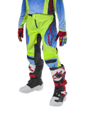 Alpinestars Youth 2024 Racer Hoen Pants, calças de motocross para jovens, amarelo néon e azul marinho com detalhes vermelhos, usadas com luvas a condizer e botas brancas, pretas e vermelhas, com um corte desportivo e pernas pré-curvadas para corridas de todo-o-terreno