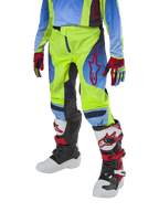Alpinestars Youth 2024 Racer Hoen Pants, calças de motocross para jovens, amarelo néon e azul marinho com detalhes vermelhos, usadas com luvas a condizer e botas brancas, pretas e vermelhas, com um corte desportivo e pernas pré-curvadas para corridas de todo-o-terreno
