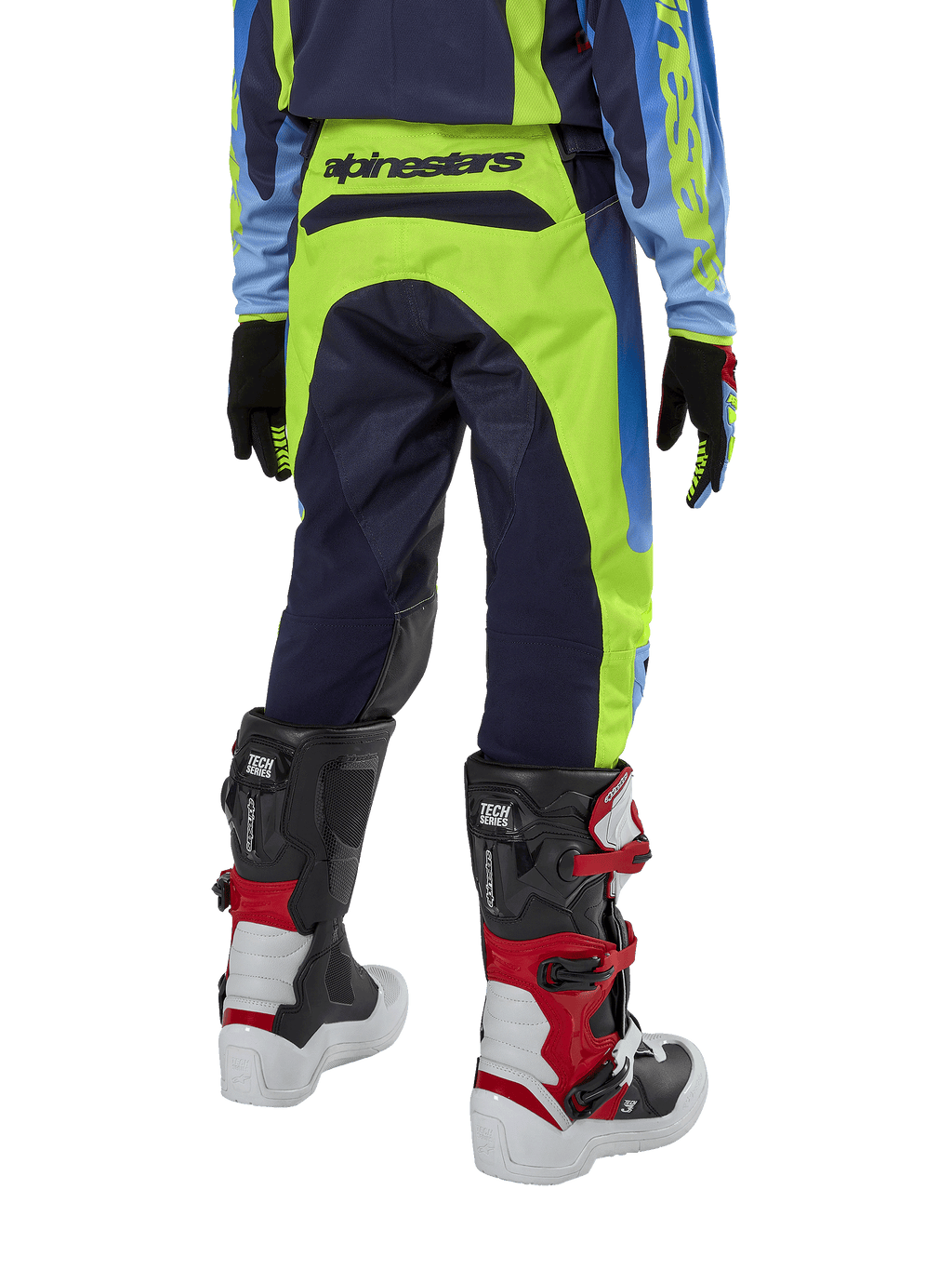 Alpinestars Youth 2024 Racer Hoen Pants, calças de motocross, amarelo néon e azul marinho, vista traseira mostrando a marca Alpinestars em destaque no cós, usadas com botas Tech Series pretas e vermelhas e camisola a condizer, ajuste desportivo durável para jovens pilotos de todo-o-terreno