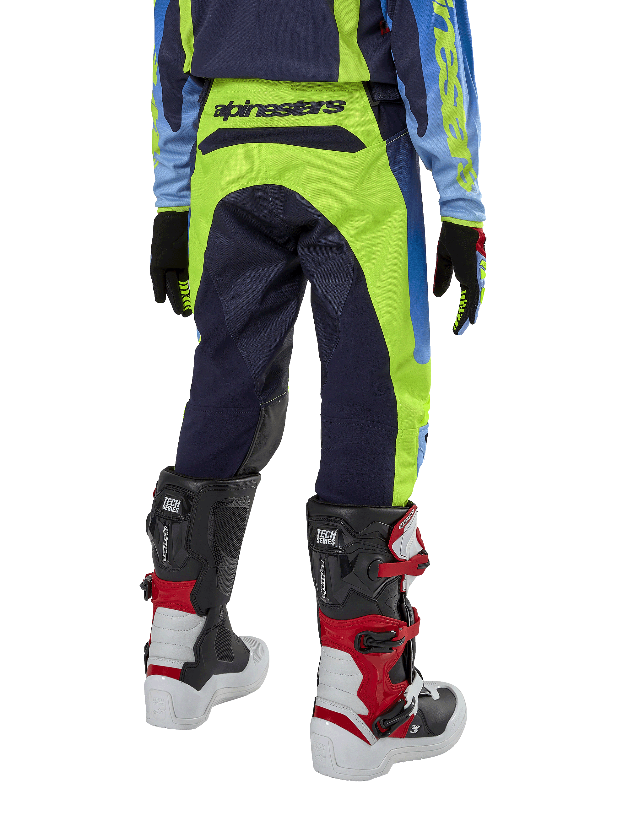 Alpinestars Youth 2024 Racer Hoen Pants, calças de motocross, amarelo néon e azul marinho, vista traseira mostrando a marca Alpinestars em destaque no cós, usadas com botas Tech Series pretas e vermelhas e camisola a condizer, ajuste desportivo durável para jovens pilotos de todo-o-terreno