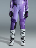 Alpinestars 2026 Woman Stella Fluid Apex Pants, calças de motocross, violeta e branco, usadas com luvas pretas e violeta e botas brancas e pretas, com logótipo branco de destaque na perna, design ergonómico de ajuste desportivo para corridas off-road