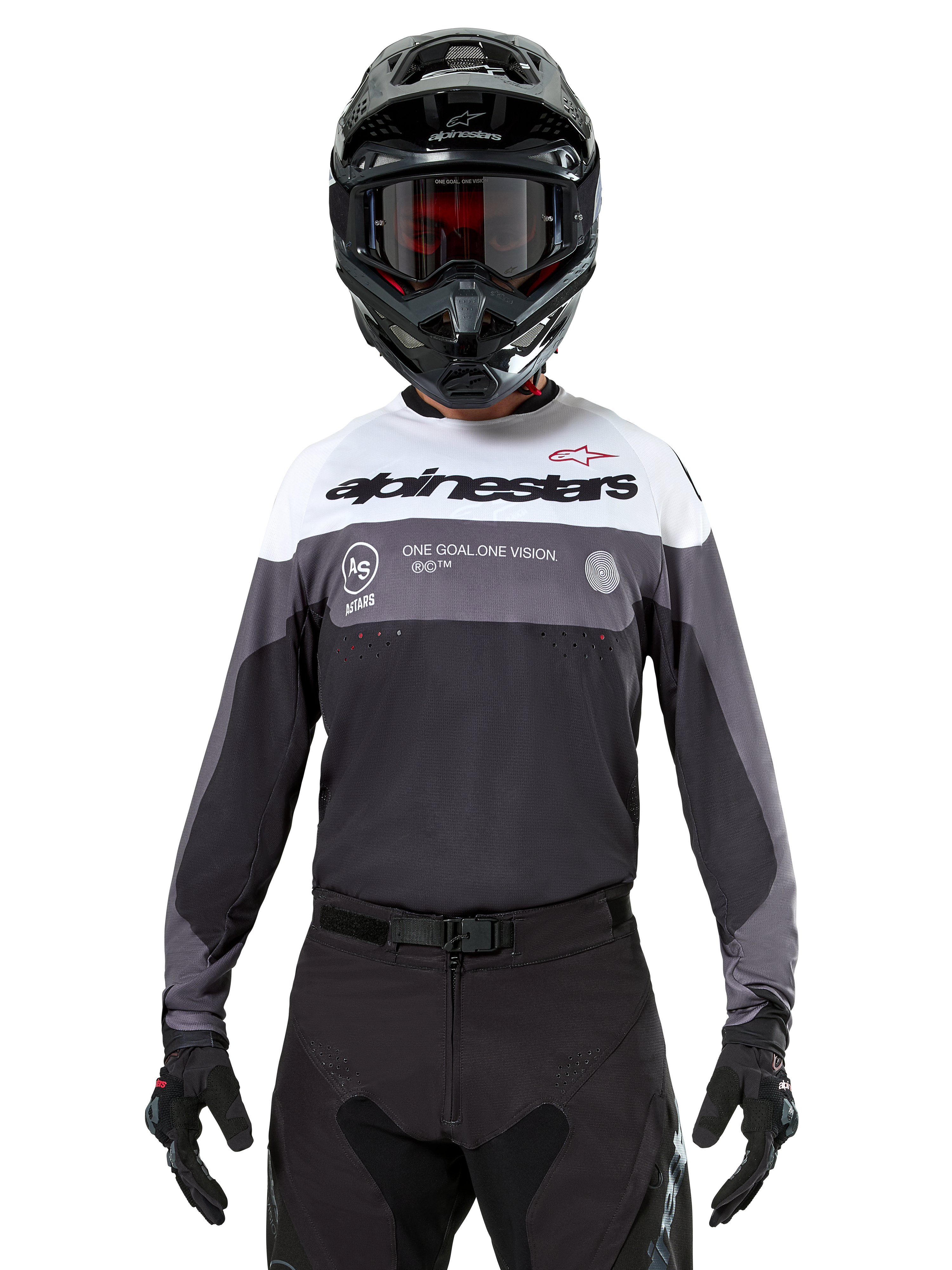 Motocross rider wearing the Alpinestars Pro-Dura Jersey in Black Magnet White, long-sleeve performance top with white and grey color blocks, worn with a black helmet and goggles, featuring 'alpinestars' branding and 'ONE GOAL ONE VISION' slogan, off-road motorcycle racing apparel