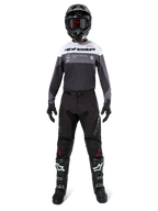Piloto de motocross com equipamento completo, Camisola Pro-Dura em Black Magnet White com a parte superior do peito branca e detalhes cinzentos, calças pretas, capacete preto com óculos escuros, botas brancas e pretas e luvas pretas, conjunto coordenado para enduro e off-road