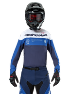 Camisola Alpinestars Pro-Dura, camisola de motocross e enduro, azul marinho, azul vivo e branco, usada com calças azul marinho a condizer, luvas e capacete pretos, com logótipo no peito e ventilação cortada a laser para corridas de motos todo-o-terreno
