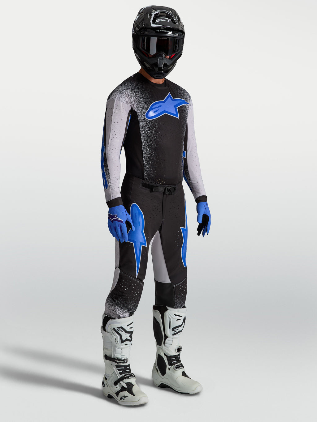 Alpinestars Supertech Hiten AFD Gear Set e Camisola, conjunto de motocross para homem, preto e azul com botas brancas.
