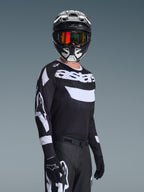 Piloto de motocross a usar a Camisola Racer Air Riway 2026, camisola preta e branca com o logótipo 'astars', capacete preto e branco a condizer com óculos espelhados cor de laranja, calças e luvas de motocross pretas, conjunto coordenado para todo-o-terreno