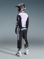 Motocross rider viewed from behind wearing the Alpinestars 2026 Racer Air Riway Gear Set in Black and White, featuring a ventilated mesh jersey back and large white branding, styled with a matching black helmet and white boots.
