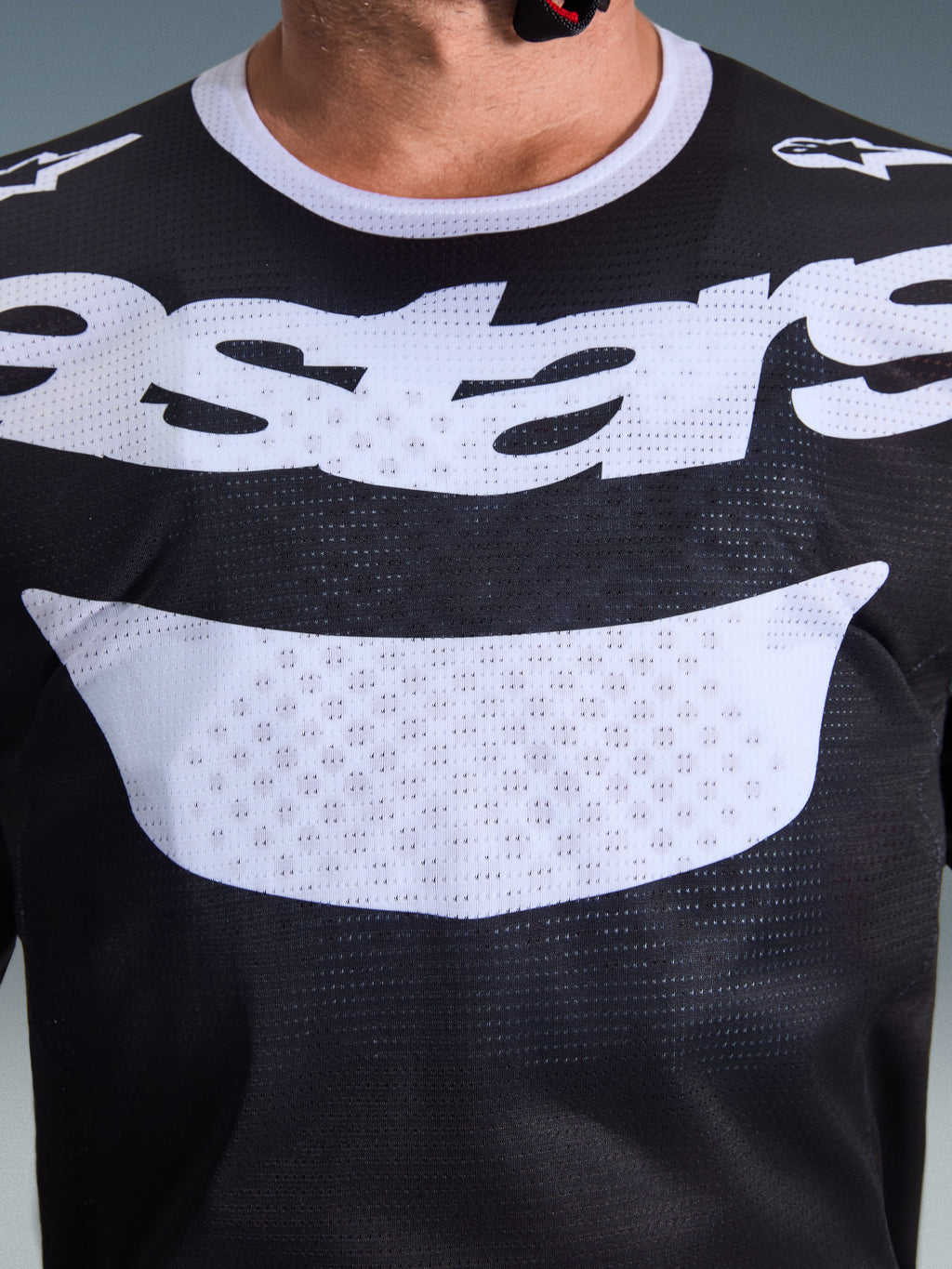 Camisola Alpinestars 2026 Racer Air Riway, camisola de motocross, preta e branca, vista em grande plano do peito com logótipo branco grande, textura detalhada do tecido de malha respirável, equipamento técnico para condução off-road