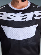 Camisola Alpinestars 2026 Racer Air Riway, camisola de motocross, preta e branca, vista em grande plano do peito com logótipo branco grande, textura detalhada do tecido de malha respirável, equipamento técnico para condução off-road