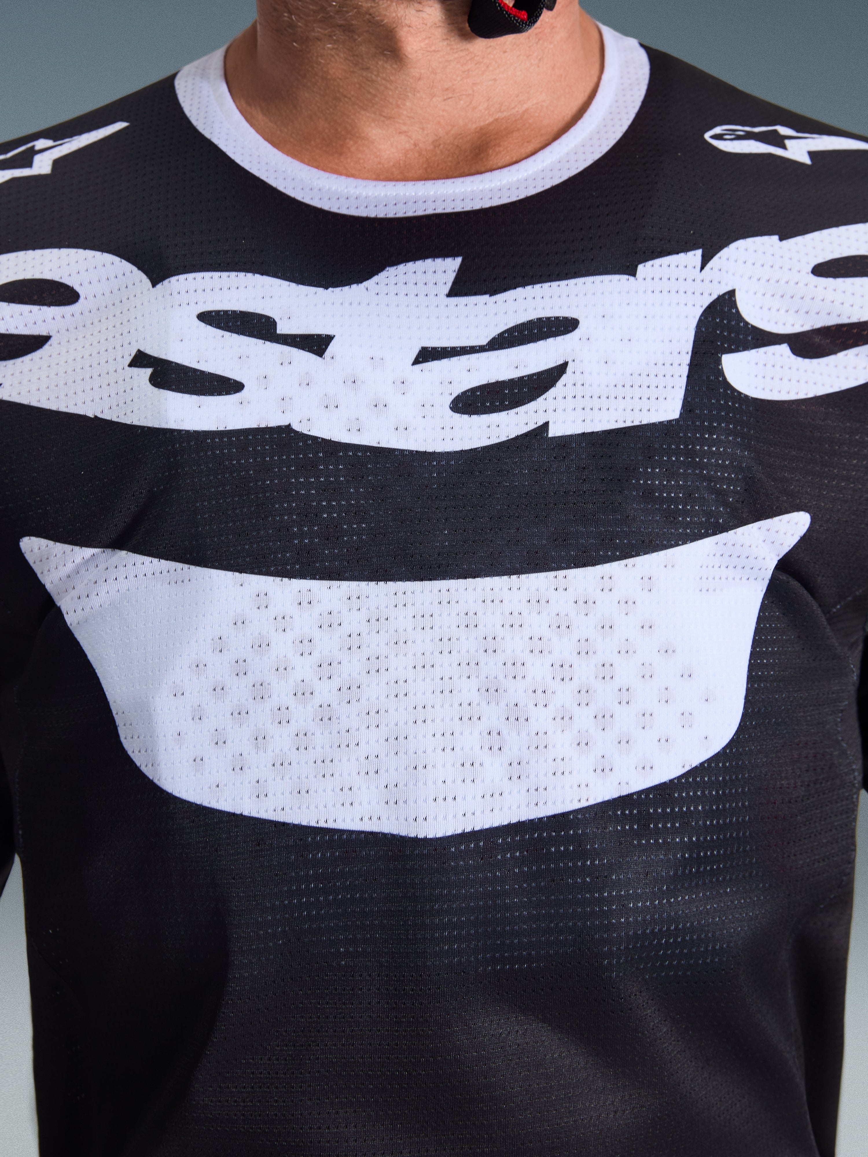Camisola Alpinestars 2026 Racer Air Riway, camisola de motocross, preta e branca, vista em grande plano do peito com logótipo branco grande, textura detalhada do tecido de malha respirável, equipamento técnico para condução off-road
