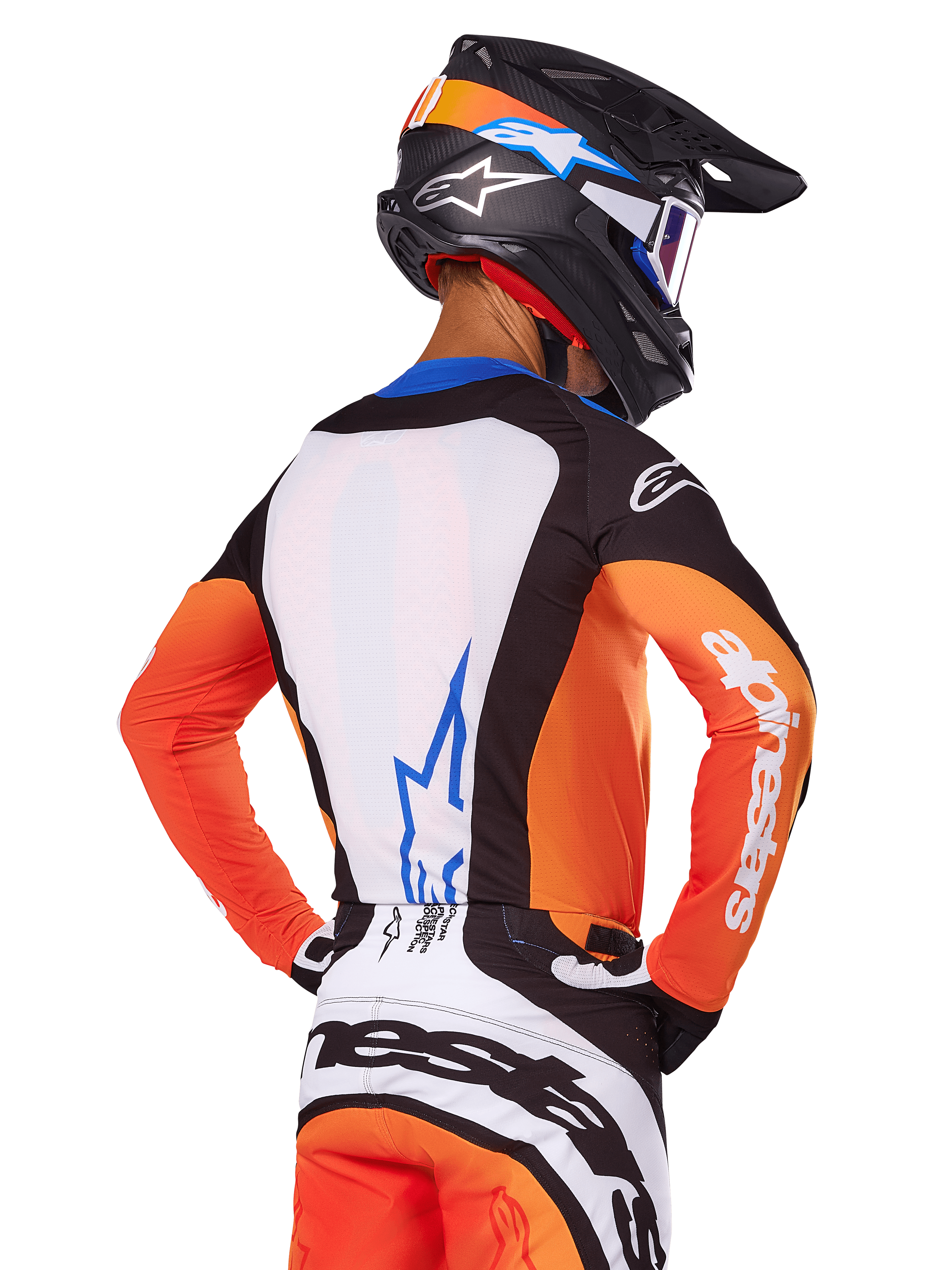 Piloto de motocross com a Camisola Alpinestars Techstar Melt 2025, laranja e azul, vista traseira mostrando o painel branco com logótipo azul, mangas cor de laranja com logótipo branco, capacete e calças de motocross a condizer, equipamento profissional de competição