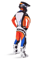 Piloto de motocross visto de costas a usar o conjunto de equipamento Techstar Melt 2025, camisola laranja e azul com painel traseiro branco e logótipo de estrela azul, calças laranja e azul a condizer com marca Alpinestars branca, capacete preto com grafismos azuis e botas de motocross brancas, conjunto de corrida todo-o-terreno coordenado.