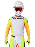 Alpinestars 2025 Techstar Melt Jersey, equipamento de motocross, peito branco com mangas amarelo néon e laranja, piloto com capacete branco e óculos vermelhos, luvas amarelo néon com logótipos pretos, cores vibrantes para desempenho em todo-o-terreno