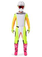 Alpinestars 2025 Techstar Melt Jersey, piloto de motocross com equipamento completo, camisola branca e amarela com mangas laranja, calças amarelas a condizer, botas cor-de-rosa vibrante, capacete branco com óculos vermelhos, kit de corrida todo-o-terreno coordenado