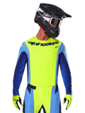 Camisola Techstar Melt 2025, camisola de motocross, amarelo fluo e azul, com ventilação cortada a laser e ajuste de corrida, usada por um piloto com capacete preto e luvas amarelo fluo
