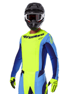 Conjunto de Equipamento Alpinestars 2025 Techstar Melt, piloto de motocross com camisola amarela e azul vibrante e calças a condizer, capacete preto com óculos brancos e pretos, luvas amarelas, conjunto de corrida todo-o-terreno coordenado com logótipos Alpinestars em destaque e pormenores perfurados