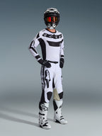Conjunto de Equipamento Alpinestars 2026 Racer Riway, piloto de motocross com kit de corrida branco e preto, camisola branca com logótipo 'astars' preto no peito, calças brancas com detalhes pretos, capacete preto com óculos cor de laranja, botas brancas, equipamento coordenado para motocross e condução off-road
