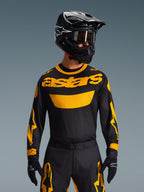 Alpinestars 2026 Racer Riway Gear Set, motocross rider wearing black jersey with bold yellow 'astars' logo, matching black pants with yellow accents, black helmet and goggles, black gloves, professional off-road racing gear