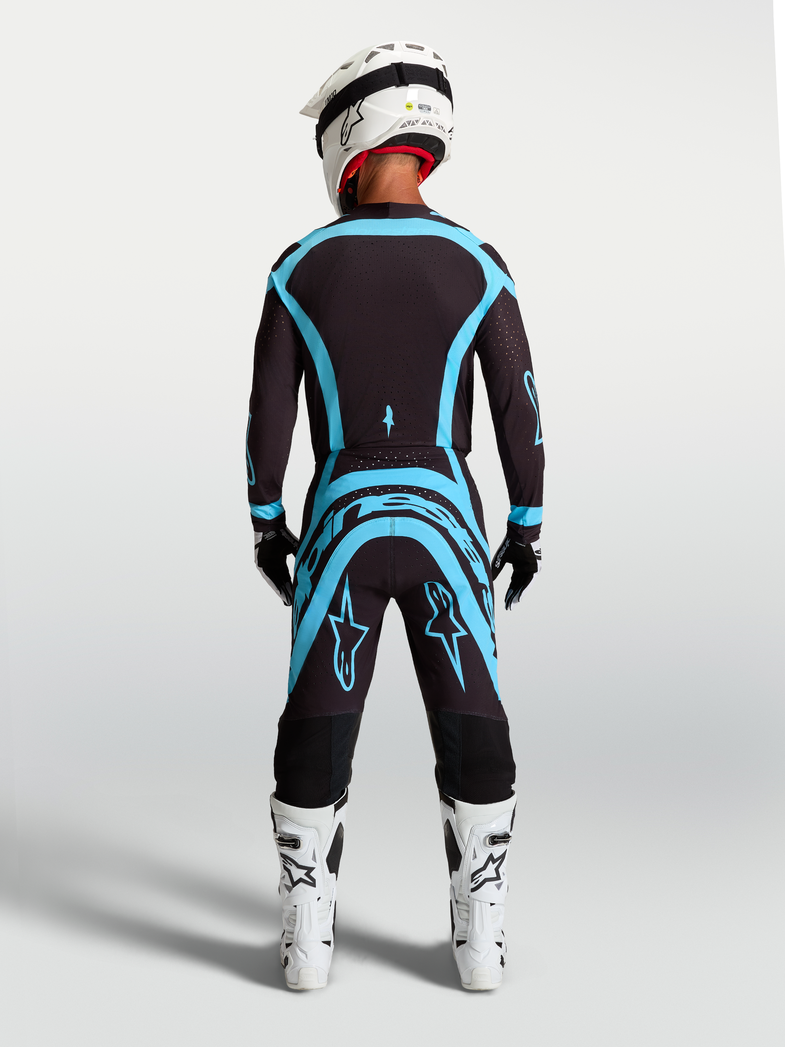 Conjunto Alpinestars Supertech Vesta, camisola e calças de motocross, pretas e turquesa, vista traseira, ajuste atlético.