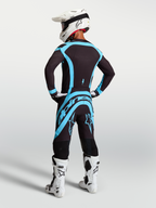 Camisola e conjunto Supertech Vesta da Alpinestars, equipamento de motocross preto e turquesa com ajuste atlético elástico.