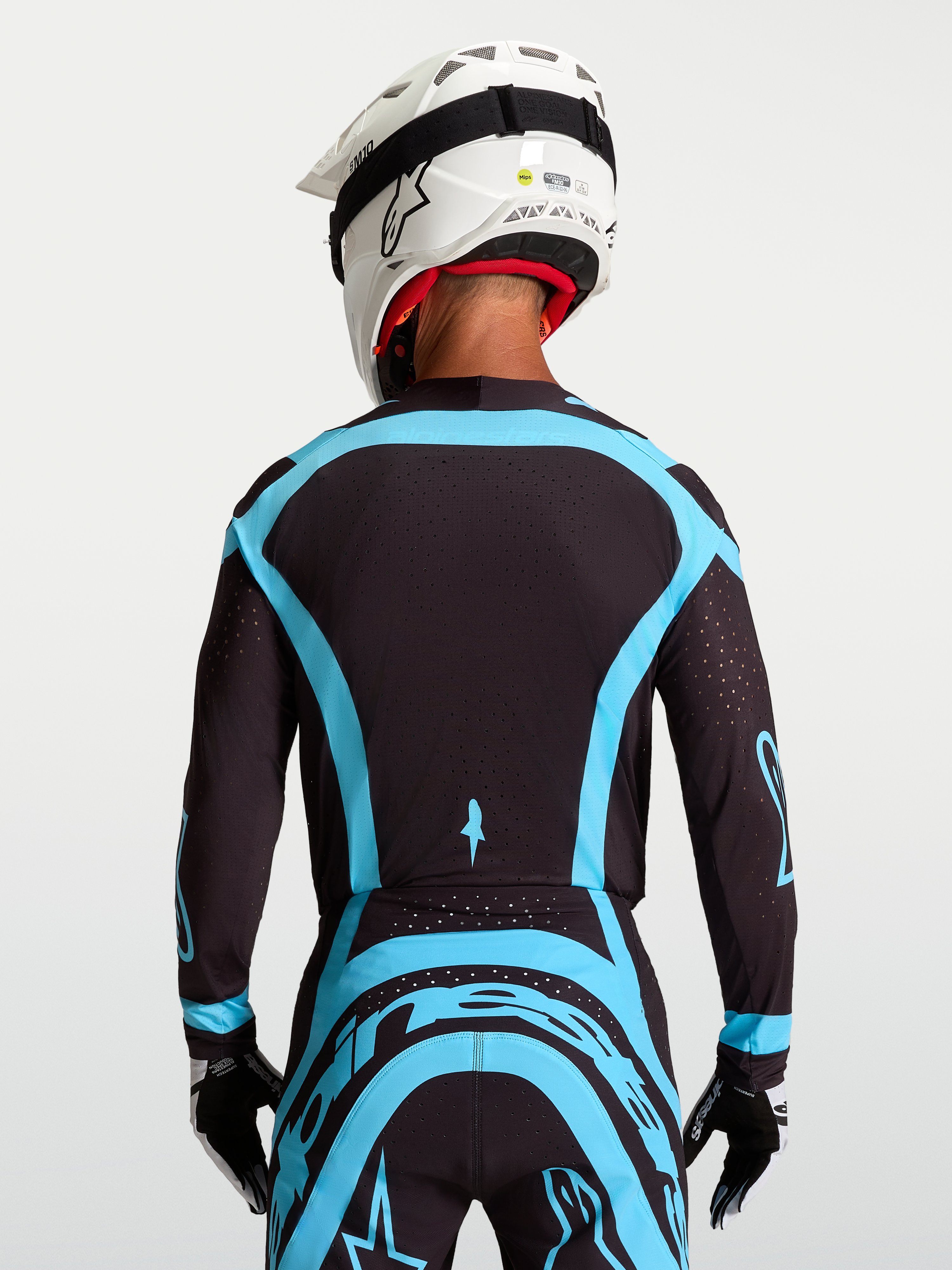 Alpinestars Supertech Vesta, camisola de motocross de nível profissional para homem, preta e turquesa, vista traseira em malha elástica com perfurações a laser.