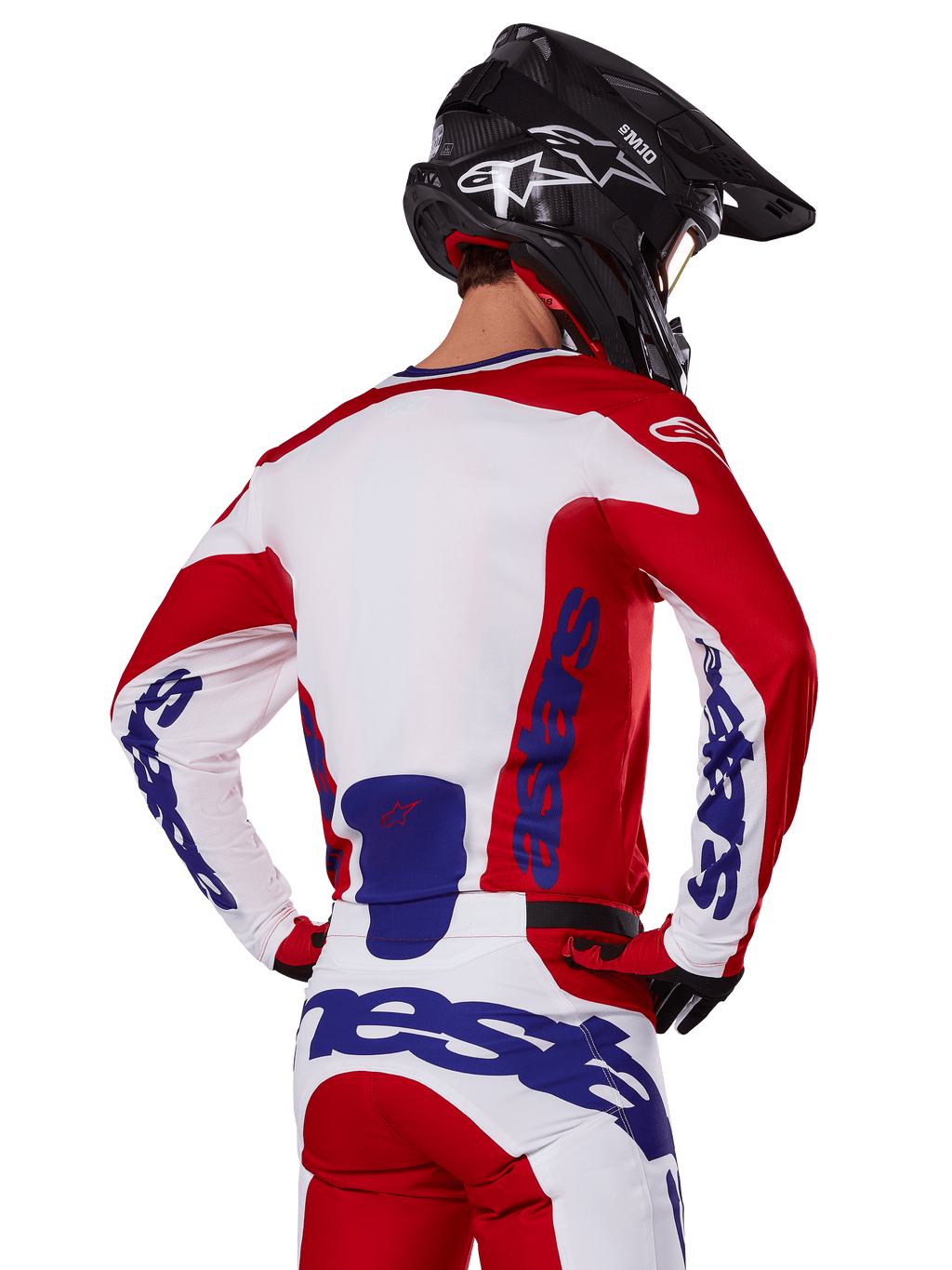 Alpinestars 2025 Racer Veil Jersey and Pants, conjunto de equipamento de motocross, vermelho vivo, branco e azul, vista traseira do piloto a usar o equipamento a condizer e capacete de motocross preto, com a marca Alpinestars em azul em destaque, vestuário técnico de corrida para todo-o-terreno