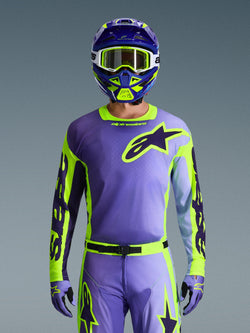 Camisola Alpinestars 2026 Racer Portl, camisola de motocross, roxo e amarelo néon, usada com calças, luvas e capacete de motocross a condizer, com um grande logótipo de estrela da Alpinestars no peito, fotografia de estúdio contra um fundo cinzento.