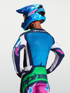 Alpinestars Camisola Techstar Maven, equipamento de motocross para homem, azul vibrante e verde com detalhes rosa, vista traseira no modelo.