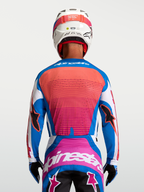 Camisola Alpinestars Techstar Maven, azul e coral, vista traseira no piloto, ajuste atlético de motocross com ventilação.