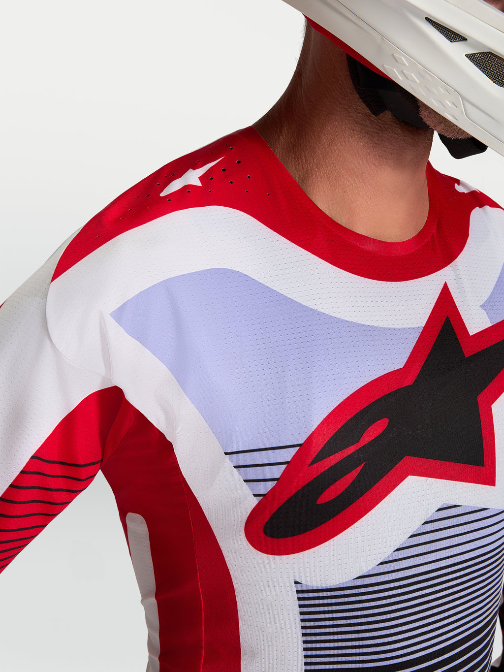 Alpinestars Camisola Techstar Maven, camisola de motocross em vermelho e lavanda, pormenor das perfurações a laser no ombro e logótipo Astars no peito