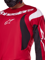 Alpinestars 2025 Fluid Haul Jersey, Bright Red and Black, close-up view of the chest and arm featuring white Alpinestars branding and logo, athletic ergonomic design with black and white swooping accents for motocross performance.