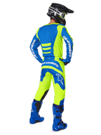 Motocross rider seen from the back wearing the Alpinestars 2025 Fluid Haul Gear Set in Yellow Fluo and Blue, featuring a blue jersey with yellow accents, yellow pants with blue panels on the seat and knees, paired with bright blue boots and a black helmet.