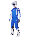Piloto de motocross com o conjunto completo de equipamento Fluid Haul 2025, camisola e calças azuis e brancas com a marca Alpinestars, capacete branco com óculos azuis, botas brancas e luvas azuis, conjunto de corrida coordenado para motocross todo-o-terreno.