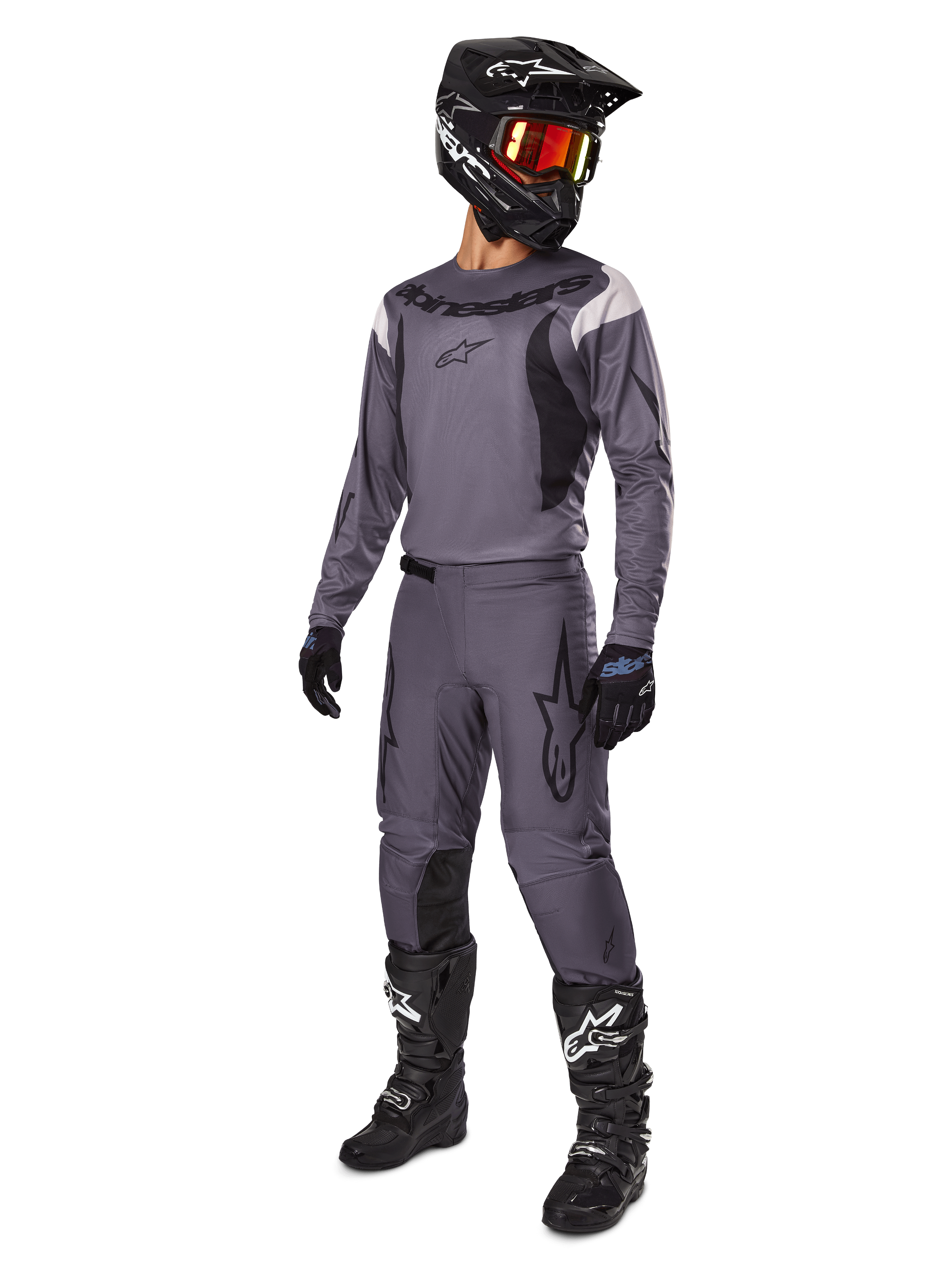 Motocross rider wearing Alpinestars 2025 Fluid Haul Gear Set in Gray, including gray jersey and pants with black accents, black helmet with reddish goggles, black gloves, and black boots with white logos, complete off-road racing outfit
