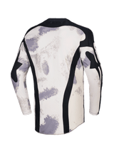 Alpinestars 2026 Racer Lahnd Jersey, camisola de motocross, camuflado areia com padrões de pinceladas em off-white e cinzento, vista traseira com painéis verticais em malha preta, gola preta e perfil traseiro alongado para maior cobertura.