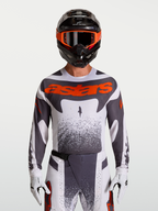 Alpinestars Techstar Swan, camisola de motocross para homem, cinzenta e branca com detalhes em vermelho fluo.