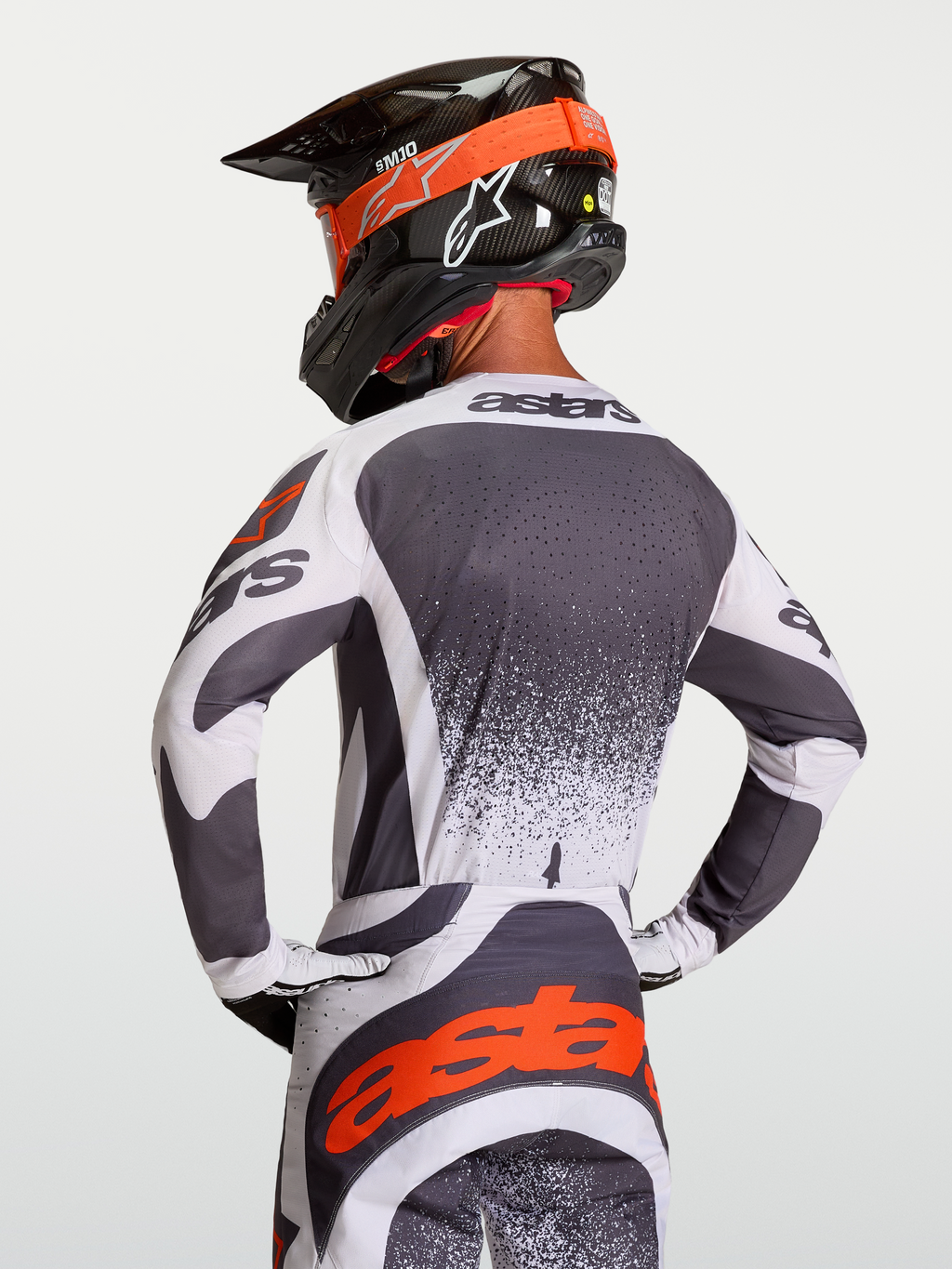 Alpinestars Camisola Techstar Swan, camisola de motocross em cinzento e branco com detalhes vermelhos, vista traseira no piloto, ajuste atlético