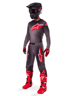 Conjunto de Equipamento Alpinestars Supertech Lipan 2025, fato completo de motocross, camisola cinzenta escura e vermelha com logótipo de estrela grande, calças a condizer com detalhes vermelhos e grafismos de estrela, luvas vermelhas e botas em vermelho vivo com fivelas brancas, incluindo capacete preto mate com óculos vermelhos