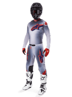 Alpinestars 2025 Supertech Lipan Gear Set, equipamento de motocross, cinzento com grafismos de estrelas em laranja fluo e azul marinho, usado com capacete preto, luvas vermelhas e pretas e botas brancas e pretas, fato profissional de off-road completo com design ventilado