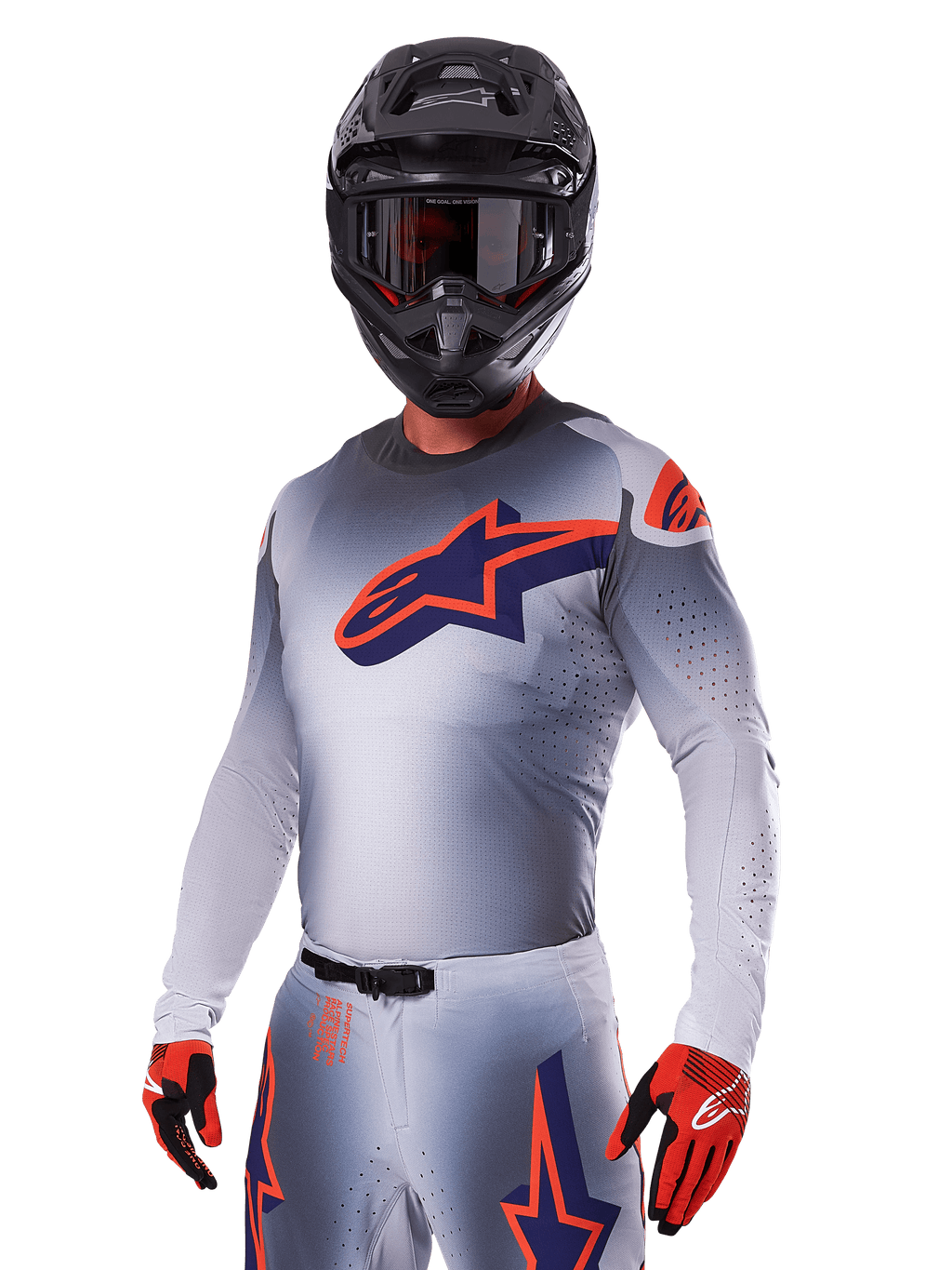 Piloto de motocross com o Conjunto de Equipamento Alpinestars Supertech Lipan 2025, camisola e calças cinzentas com detalhes em azul-marinho e laranja, capacete preto mate com óculos e luvas vermelhas e pretas, equipamento de performance atlética para corridas todo-o-terreno