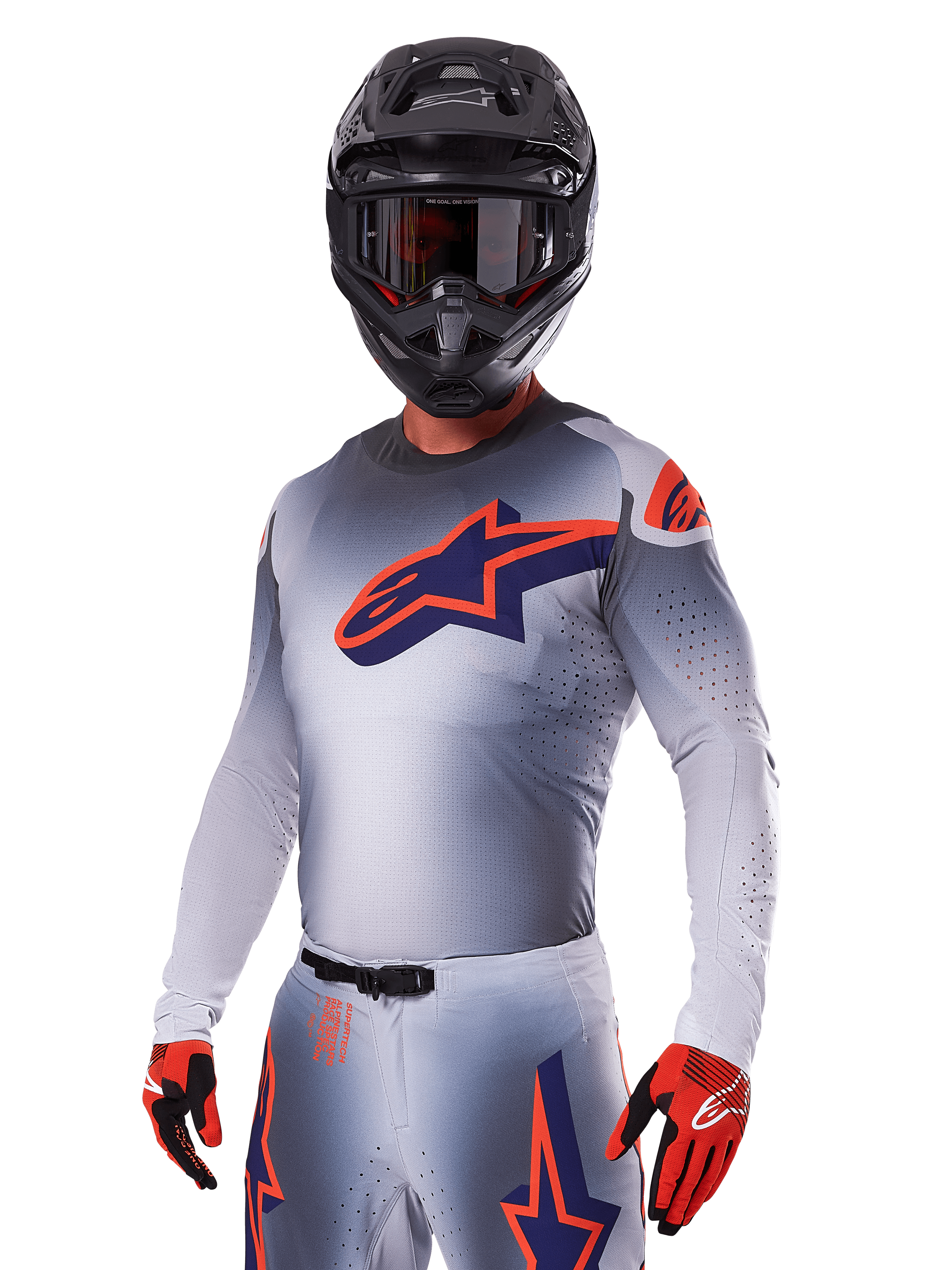 Piloto de motocross com o Conjunto de Equipamento Alpinestars Supertech Lipan 2025, camisola e calças cinzentas com detalhes em azul-marinho e laranja, capacete preto mate com óculos e luvas vermelhas e pretas, equipamento de performance atlética para corridas todo-o-terreno