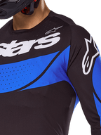 Alpinestars camisola Techstar Dreem 2025, camisola de motocross preta e azul com perfurações cortadas a laser para ventilação.
